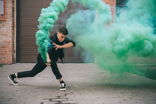 Young man dancing in green smoke on urban city street — Stock Photo