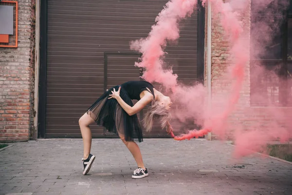 Flessibile ragazza danza in rosa fumo su strada urbana — Foto stock