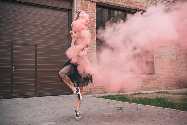 Joven bailarina contemporánea en humo rosa en la calle - foto de stock