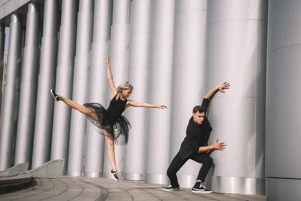 Hermosas bailarinas jóvenes en ropa negra bailando cerca de columnas - foto de stock