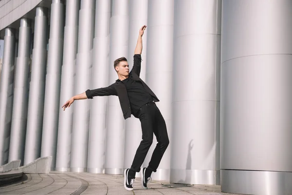 Beau jeune danseur moderne dansant près des colonnes — Photo de stock