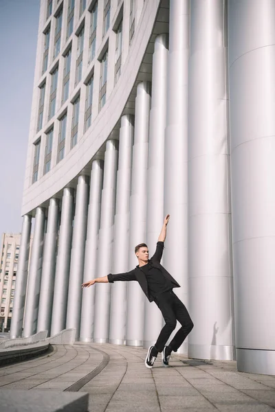 Handsome young male dancer near columns on street — Stock Photo