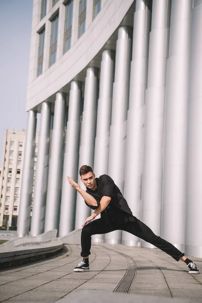 Schöner junger Mann schaut in die Kamera, während er auf der Straße tanzt — Stockfoto