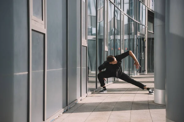 Handsome young man in black clothes dancing near columns — Stock Photo