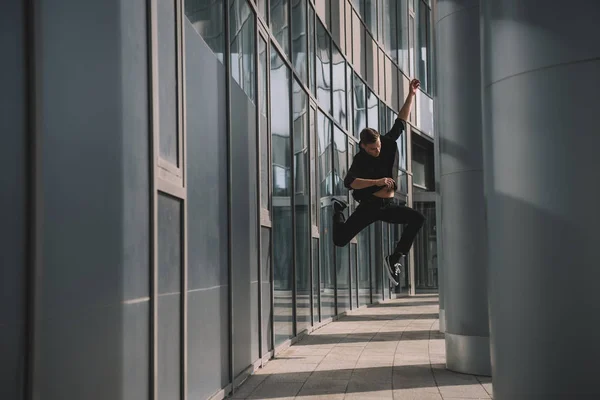Visão de comprimento total do jovem em roupas pretas pulando em dança — Fotografia de Stock