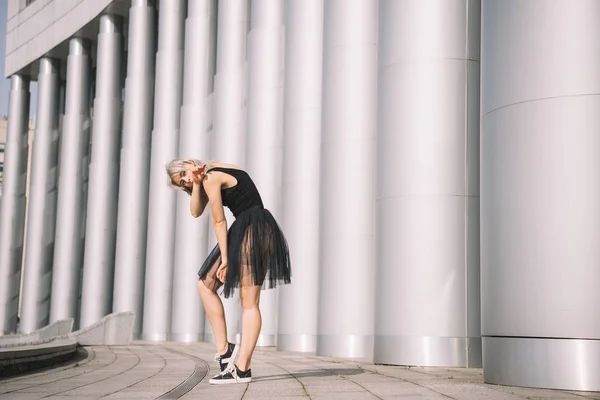 Beautiful young female dancer standing near columns on street — Stock Photo