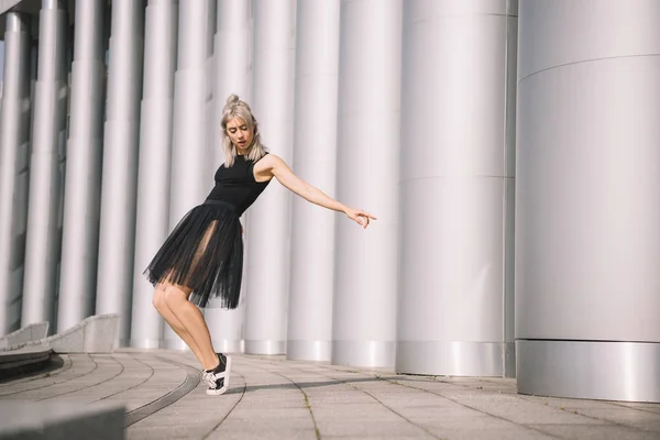 Hermosa joven en falda negra bailando cerca de columnas — Stock Photo
