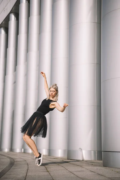 Beautiful girl in black skirt dancing near columns — Stock Photo