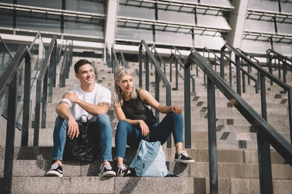 Красивая улыбающаяся молодая пара, сидящая вместе на лестнице — стоковое фото