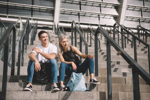 Hermosa sonriente joven pareja sentado juntos en escaleras - foto de stock