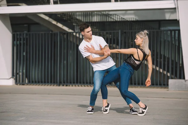 Joven pareja de bailarines contemporáneos practicando en la calle urbana de la ciudad - foto de stock