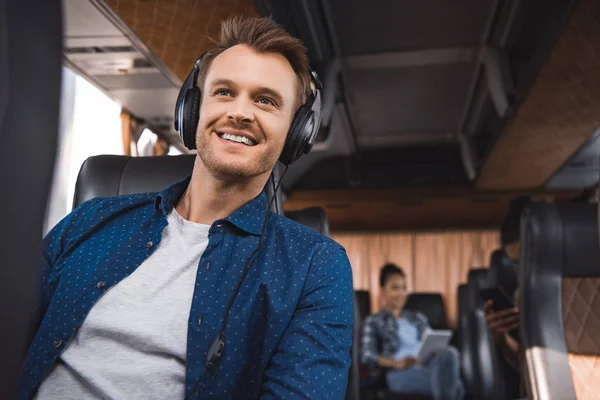 Homme joyeux dans les écouteurs écouter de la musique pendant le voyage en bus de voyage — Photo de stock