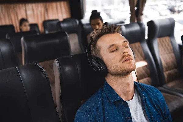 Дорослий чоловік в навушниках слухає музику і спить під час поїздки в автобусі — стокове фото