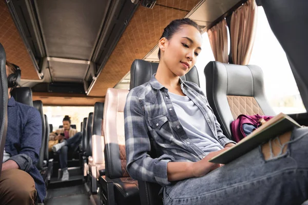 Low angle view of asian female traveler reading book during trip on travel bus — Stock Photo