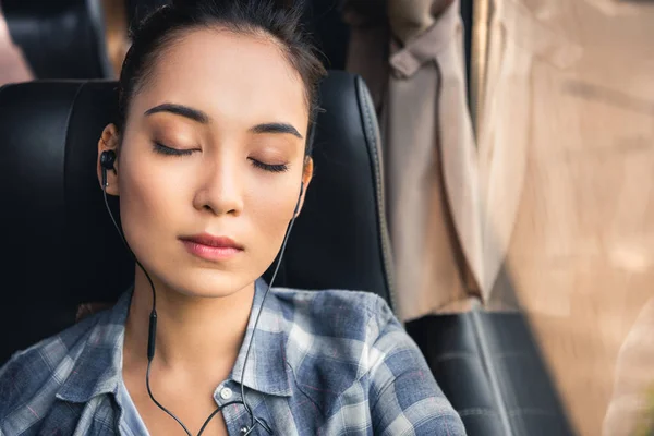 Portrait of asian woman sleeping and listening music in earphones during trip on travel bus — Stock Photo