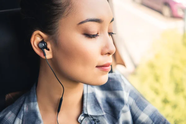 Selective focus of asian female traveler listening music in earphones during trip on bus — Stock Photo