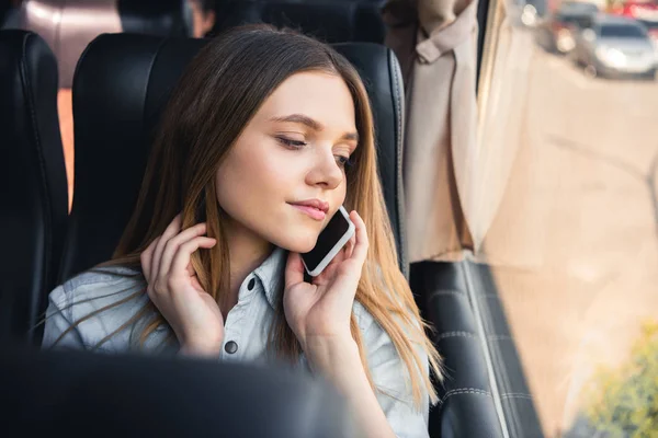Красива молода жінка розмовляє по смартфону під час поїздки в автобусі — стокове фото