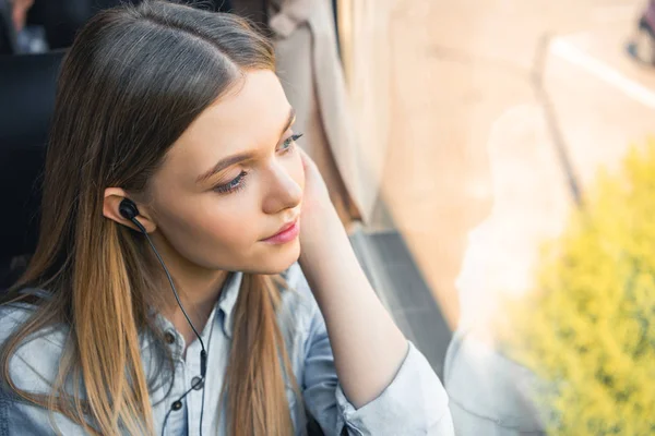 Enfoque selectivo del viajero femenino escuchando música en auriculares durante el viaje en autobús - foto de stock