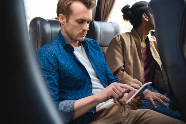 Adult man using smartphone while his friend sitting near in travel bus — Stock Photo