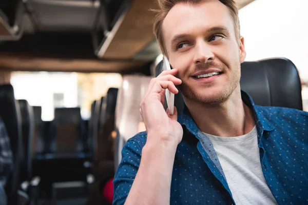 Счастливый мужчина путешественник разговаривает на смартфоне во время поездки на автобусе — стоковое фото