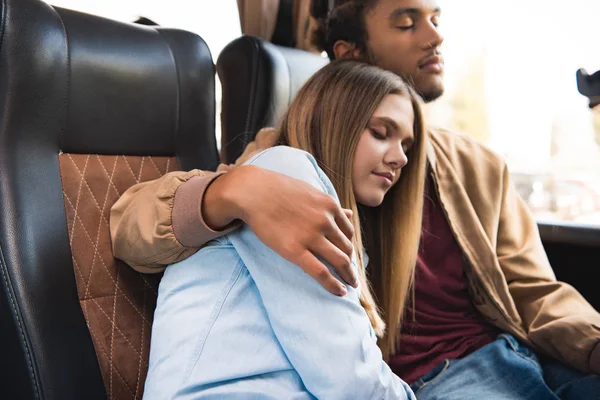 Jovem casal multicultural de turistas dormindo durante a viagem em ônibus de viagem — Fotografia de Stock