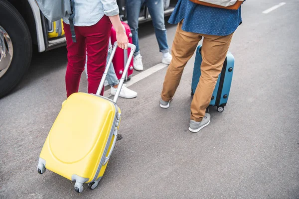Partial view of tourists with wheeled bags near travel bus at urban street — Stock Photo