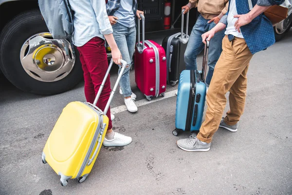 Обрізане зображення друзів з колісними сумками, що стоять біля туристичного автобуса на міській вулиці — стокове фото