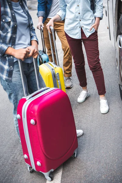 Cropped image of tourists with wheeled bags standing near travel bus at urban street — Stock Photo