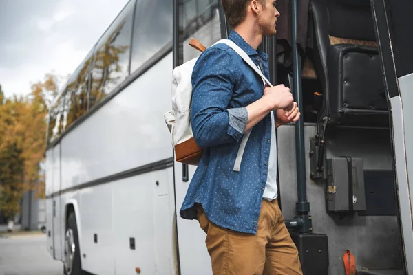 Side view of male tourist with backpack walking into travel bus at urban street — Stock Photo