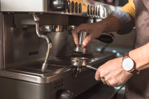 Cropped shot of barista pressing coffee into holder for coffee machine — Stock Photo