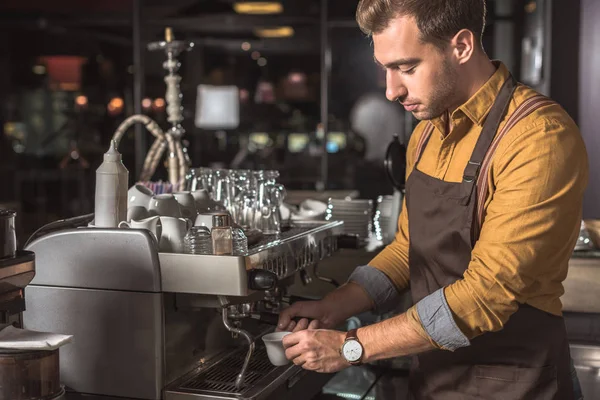 Hübsche junge Barista bereitet Kaffee mit Kaffeemaschine im Café zu — Stockfoto