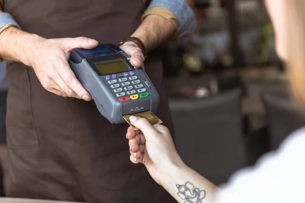 Plan recadré du serveur tenant le terminal de paiement tandis que le client insère la carte de crédit — Photo de stock
