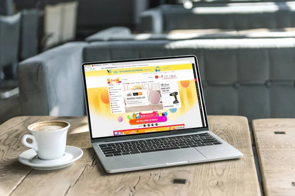 Чашка кави і ноутбук з веб-сайту aliexpress, на екрані на сільському дерев'яний стіл в кафе — стокове фото