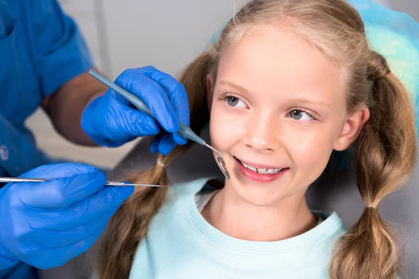 Обрізаний знімок стоматолога з інструментами, що вивчають зуби щасливої дитини — стокове фото