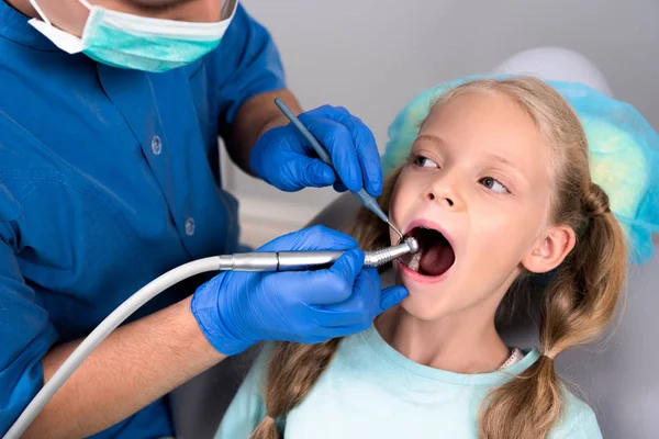 Dentista com handpiece dental trabalhando com dentes de criança — Fotografia de Stock