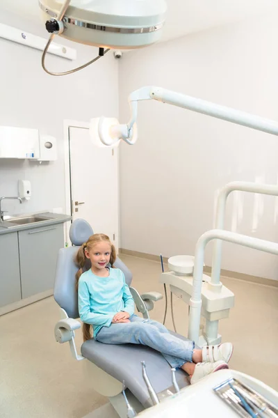 Vue grand angle de l'adorable petit enfant assis dans une chaise dentaire au bureau du dentiste — Photo de stock
