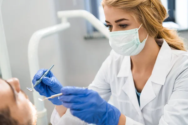 Jeune dentiste examinant les dents du client — Photo de stock