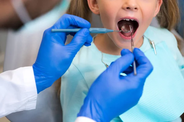 Tiro recortado de dentista examinando dentes de criança pequena — Fotografia de Stock