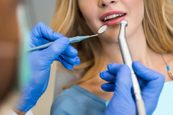 Обрезанный снимок стоматолога, осматривающего зубы клиентки — стоковое фото