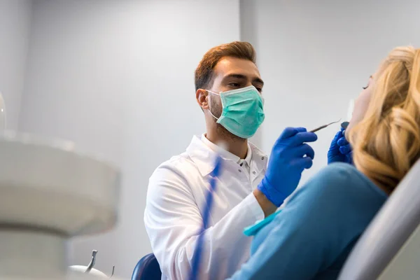 Вид снизу стоматолога в маске, осмотр зубов клиентки — стоковое фото