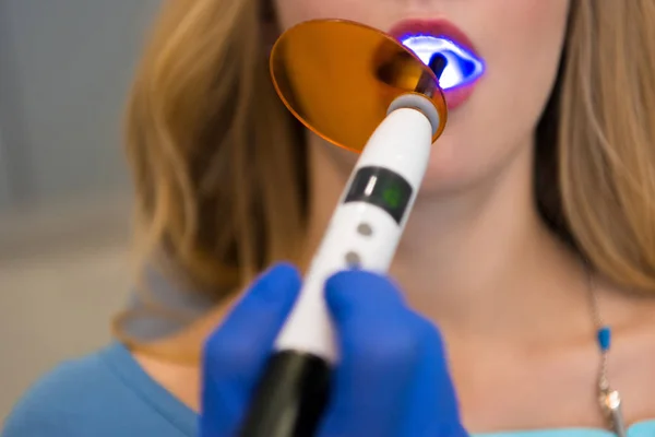 Plan recadré de dentiste avec lumière de durcissement dentaire travaillant avec le client féminin — Photo de stock