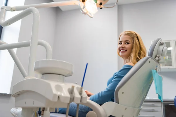 Belle jeune femme assise dans une chaise dentaire au cabinet du dentiste — Photo de stock