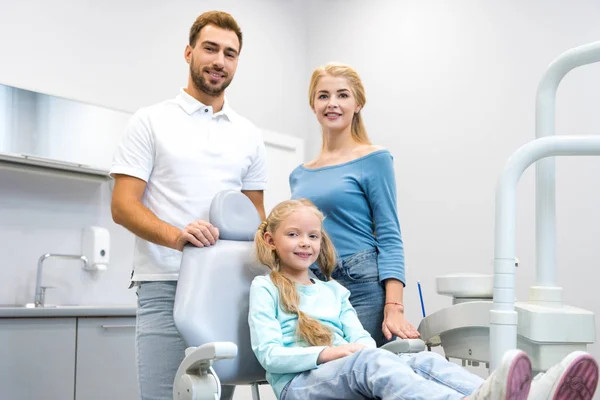 Щаслива молода сім'я дивиться на камеру в стоматологічному кабінеті — стокове фото
