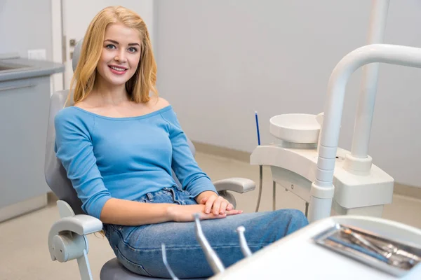 Joyeux jeune femme assise dans une chaise dentaire au cabinet du dentiste — Photo de stock