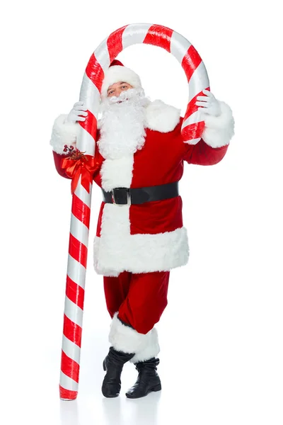 Happy santa claus standing with big christmas candy cane isolated on white — Stock Photo