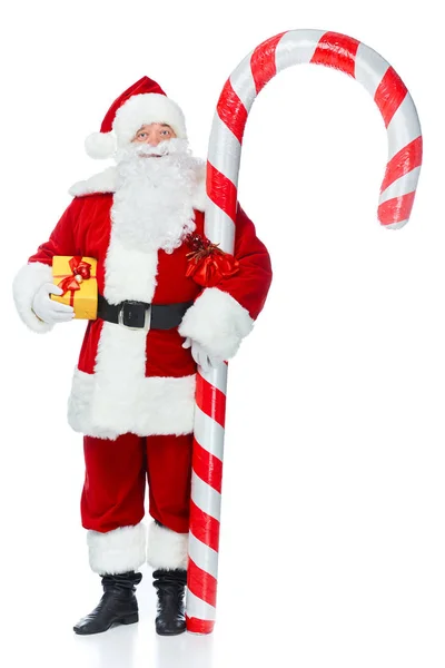 Santa claus debout avec grande canne à bonbons et cadeau de Noël isolé sur blanc — Photo de stock