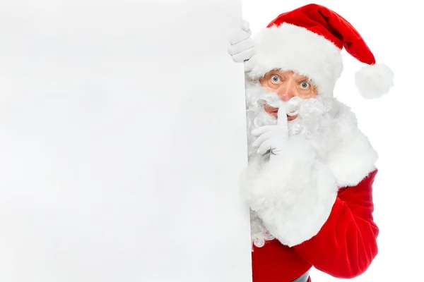 Санта-Клаус с пустым плакатом, изображающим символ тишины, изолированный на белом — стоковое фото