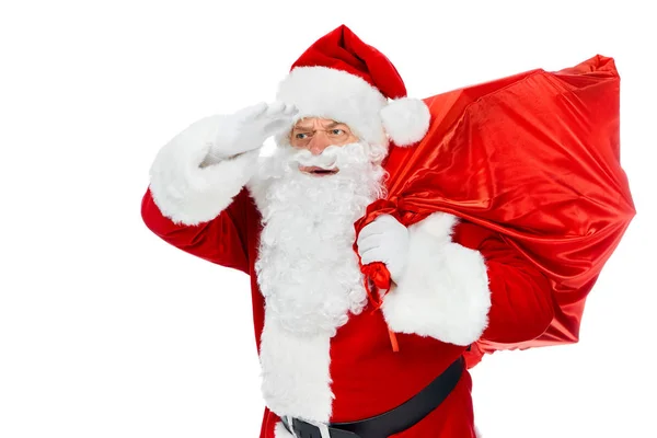 Санта-Клаус в червоній шапці тримає різдвяну сумку і дивиться ізольовано на білому — стокове фото