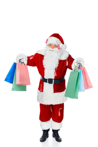 Babbo Natale in costume rosso con etichette di vendita che tengono borse della spesa isolate su bianco — Foto stock