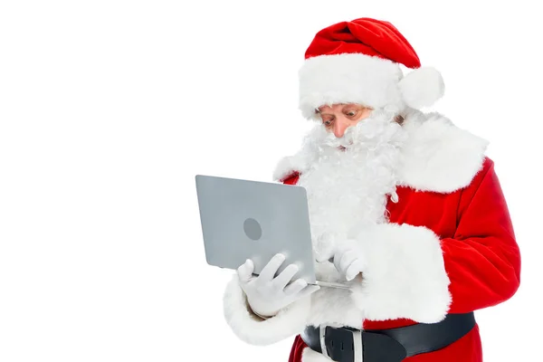 Бородатый Санта-Клаус в красном костюме с ноутбуком, изолированным на белом — стоковое фото